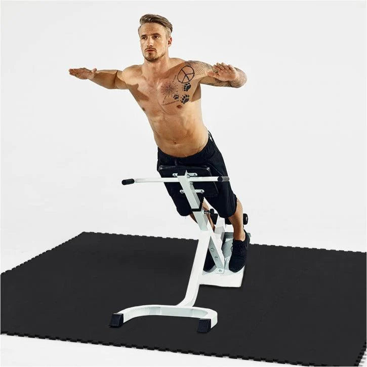 Man som tränar rygglyft på en rygglyftsbänk som är placerad på gymgolv från gorilla sports